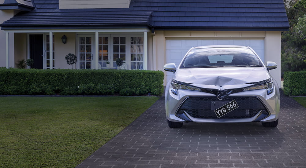Car with crumpled bonnet parked on driveway at home